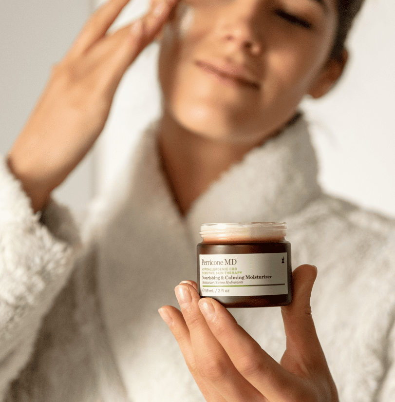 Model applying cream to her face in a dressing gown