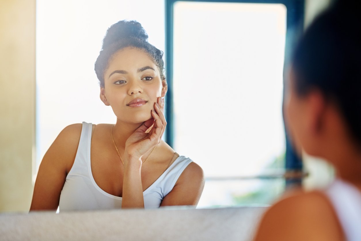 women looking into a mirror examing her skin