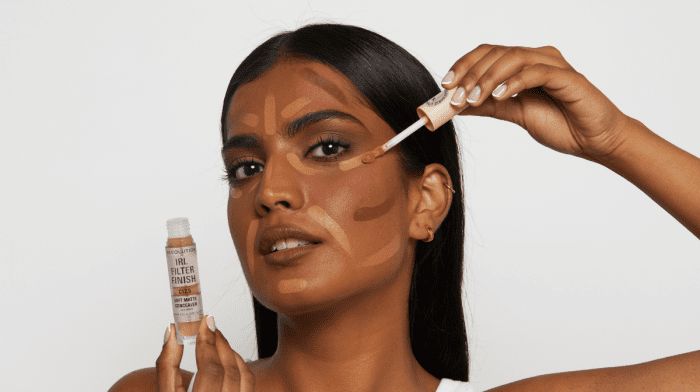 Woman applying IRL Filter Finish concealer to her face