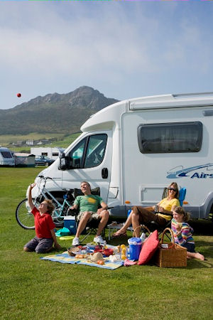Family sunbathing outside a caravan