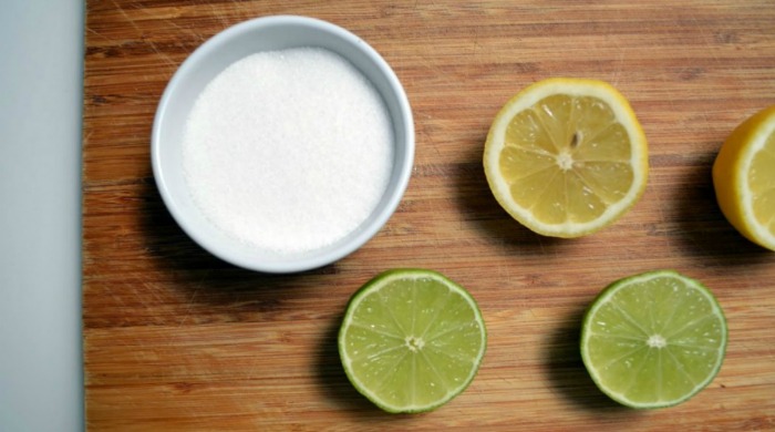 Sliced lemon, lime and a bowl of white sugar.