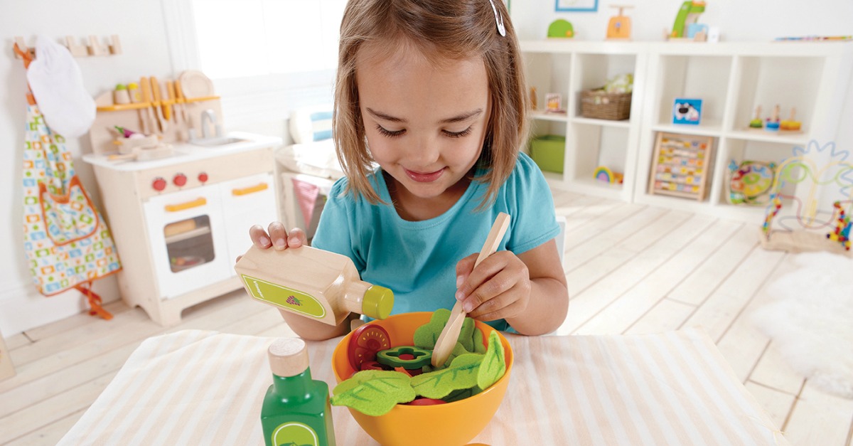 Product testers wanted: A young girl playing with a Hape Salad Set.