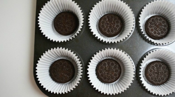 The first stage of our Oreo cupcakes recipe: Oreos placed in paper cases in a muffin tin.