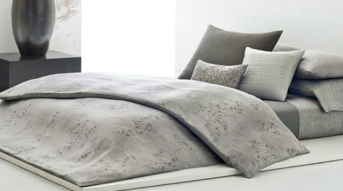 A bed made up with grey Calvin Klein Acacia bed linen.