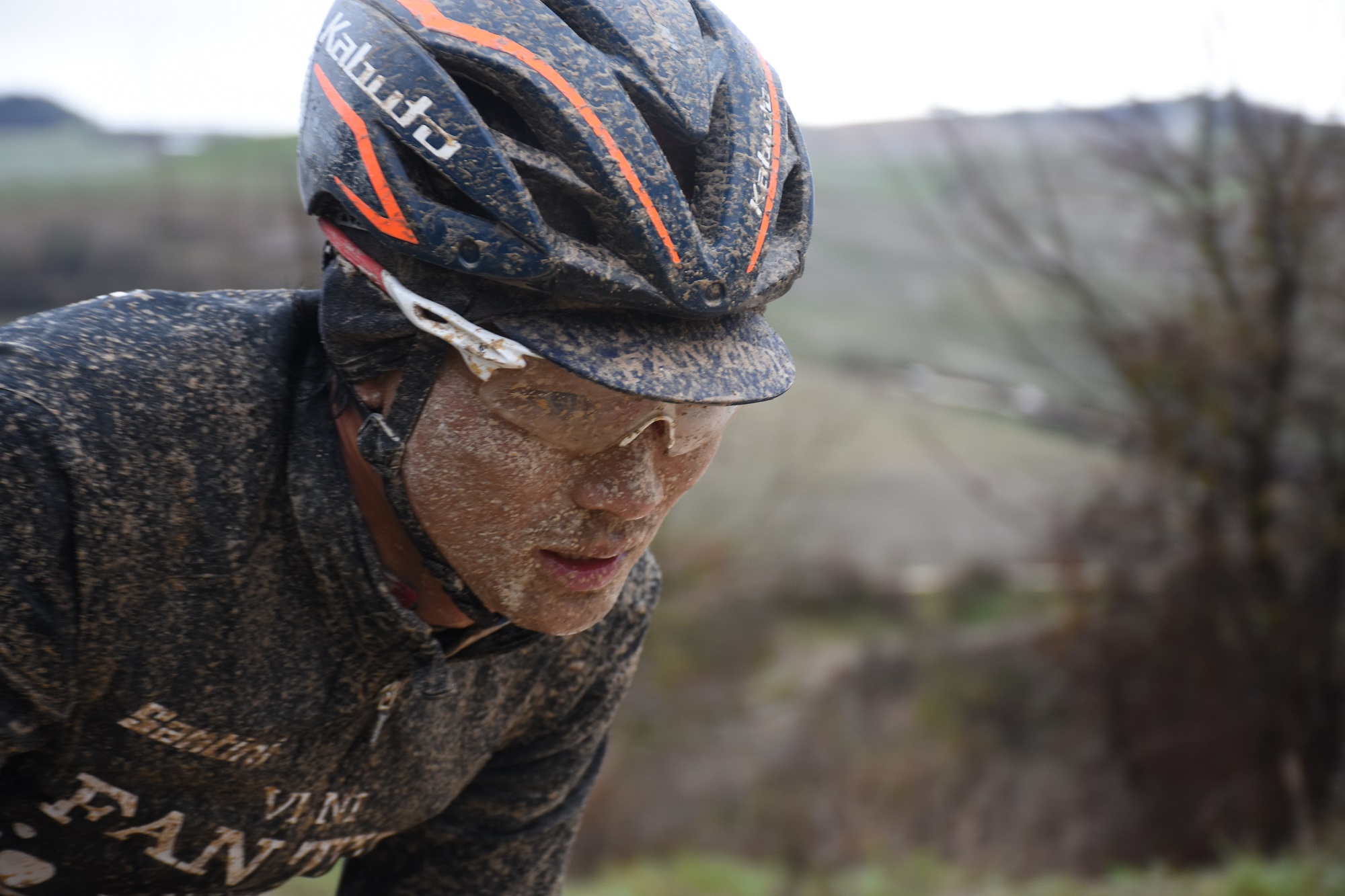 a mud-splattered rider on the dirt roads in the strade bianche 2018