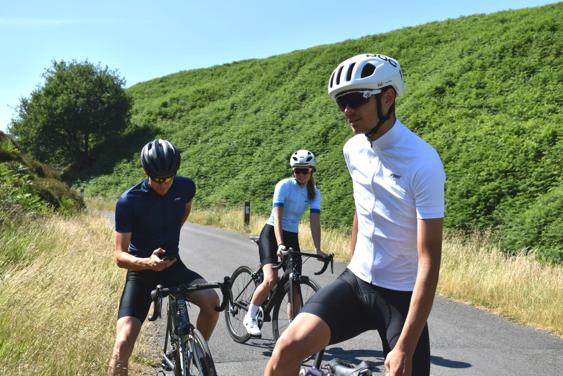 three cyclists stood wearing PBK clothing