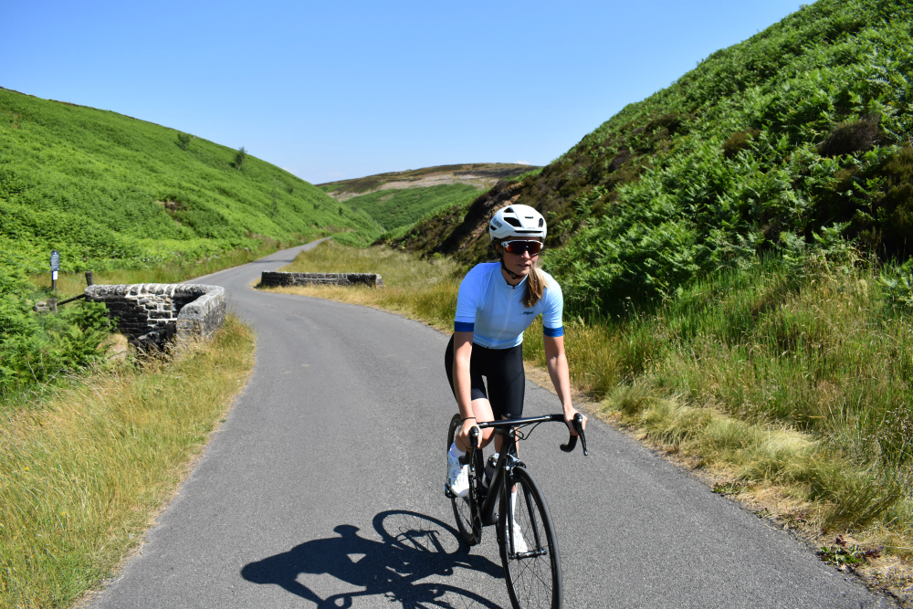 a female cyclist climbing in the new women's pbk clothing