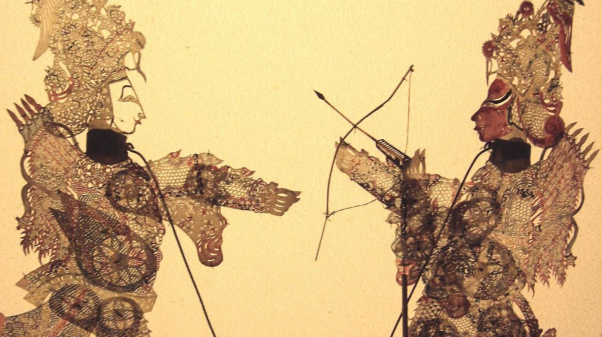 Two ornate Chinese shadow puppets projected onto beige screen. Original image has been cropped to 1200x672.