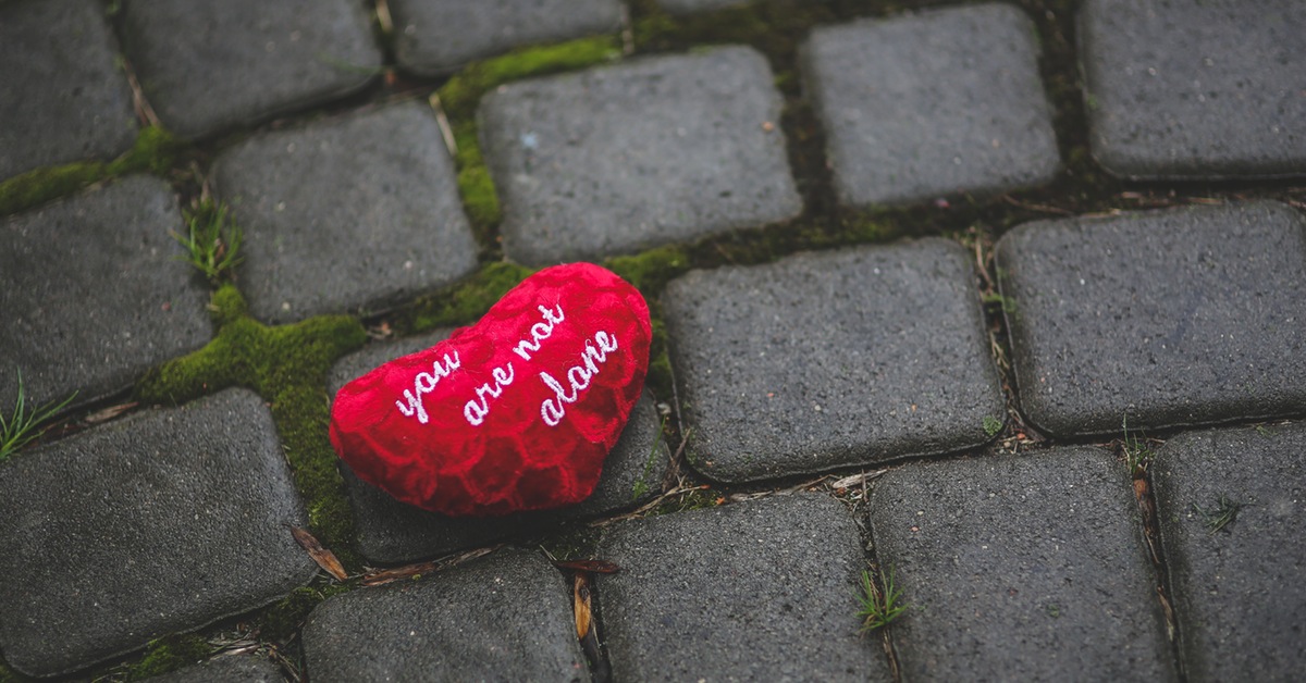 discarded loveheart-shaped cushion on grey cobbled street
