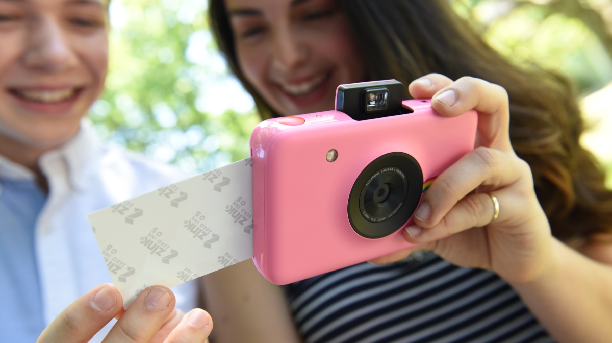 woman holding pink polaroid snap digital instant camera printing