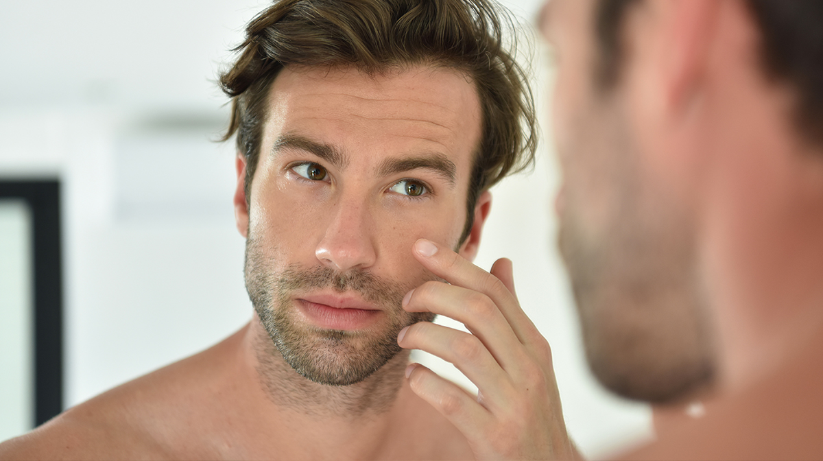 Man in front of mirror touching cheek