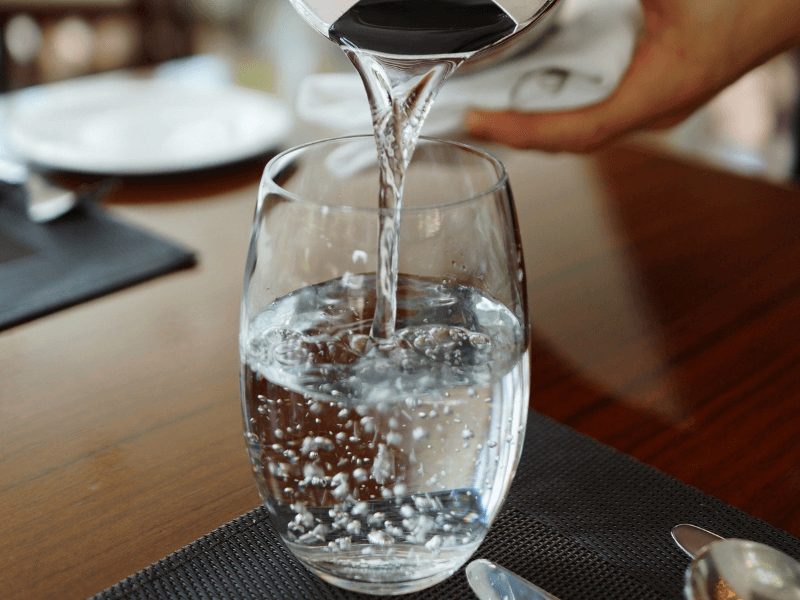 A pitcher of water being poured out into a glass