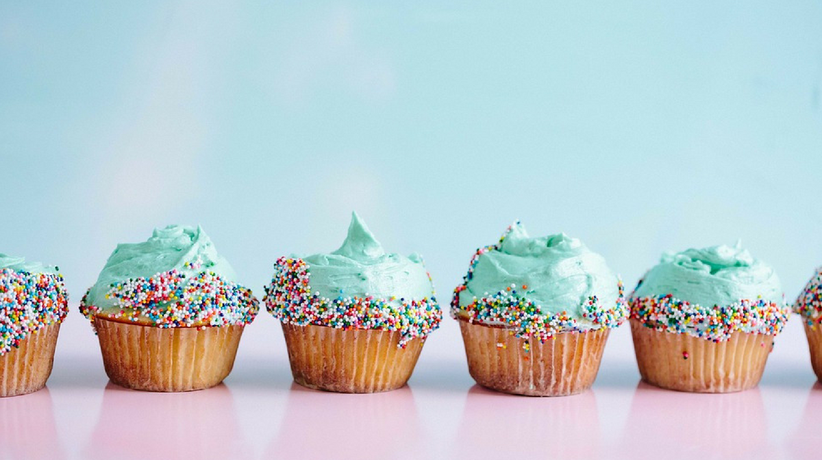 cupcakes colorate su sfondo blu: siccome ricche di zucchero, e lo zucchero fa male, andrebbero evitate