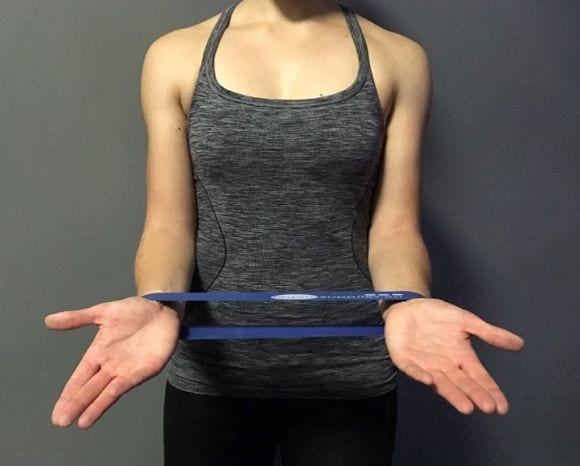 3) Das Theraband wird um die Handgelenke angebracht, dabei werden, anschließend die Handflächen auseinander zur Seite bewegt.