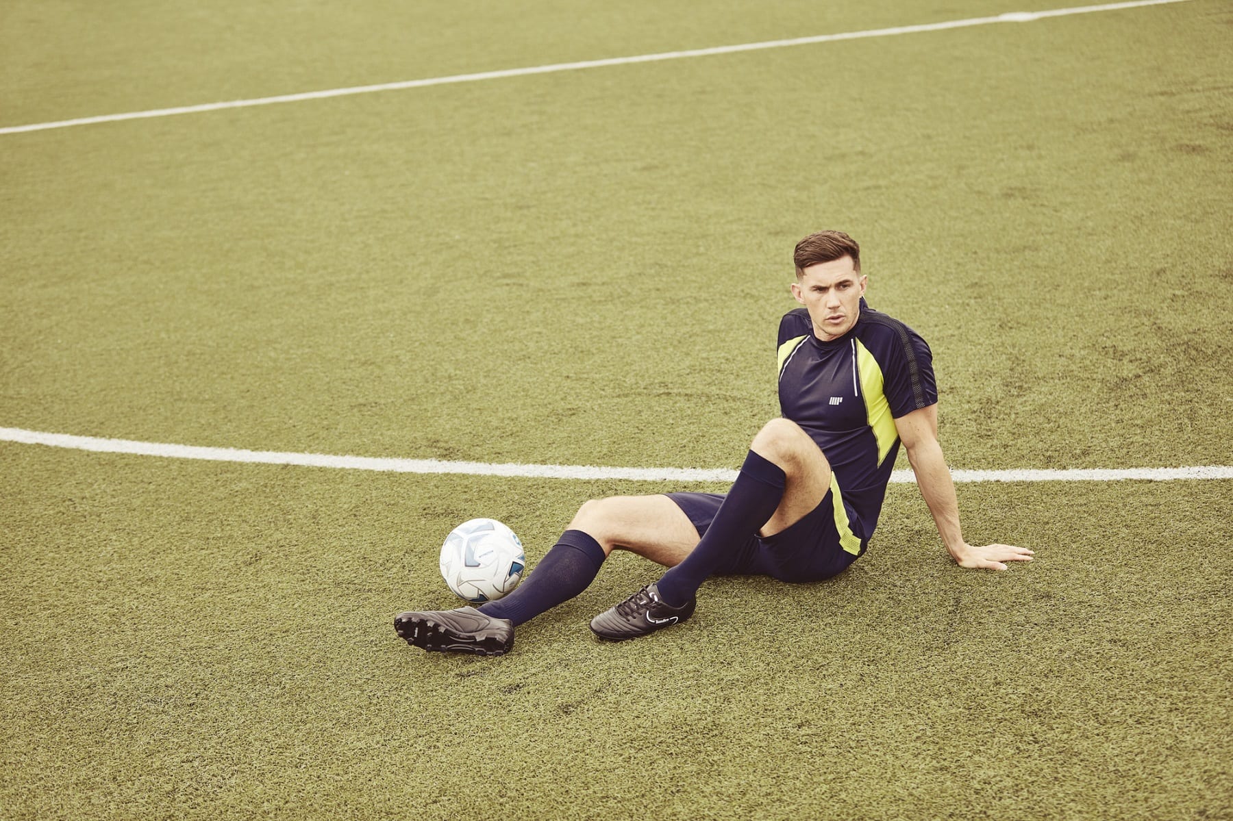 Campo de entrenamiento y piernas de un hombre con una pelota de fútbol para  un juego