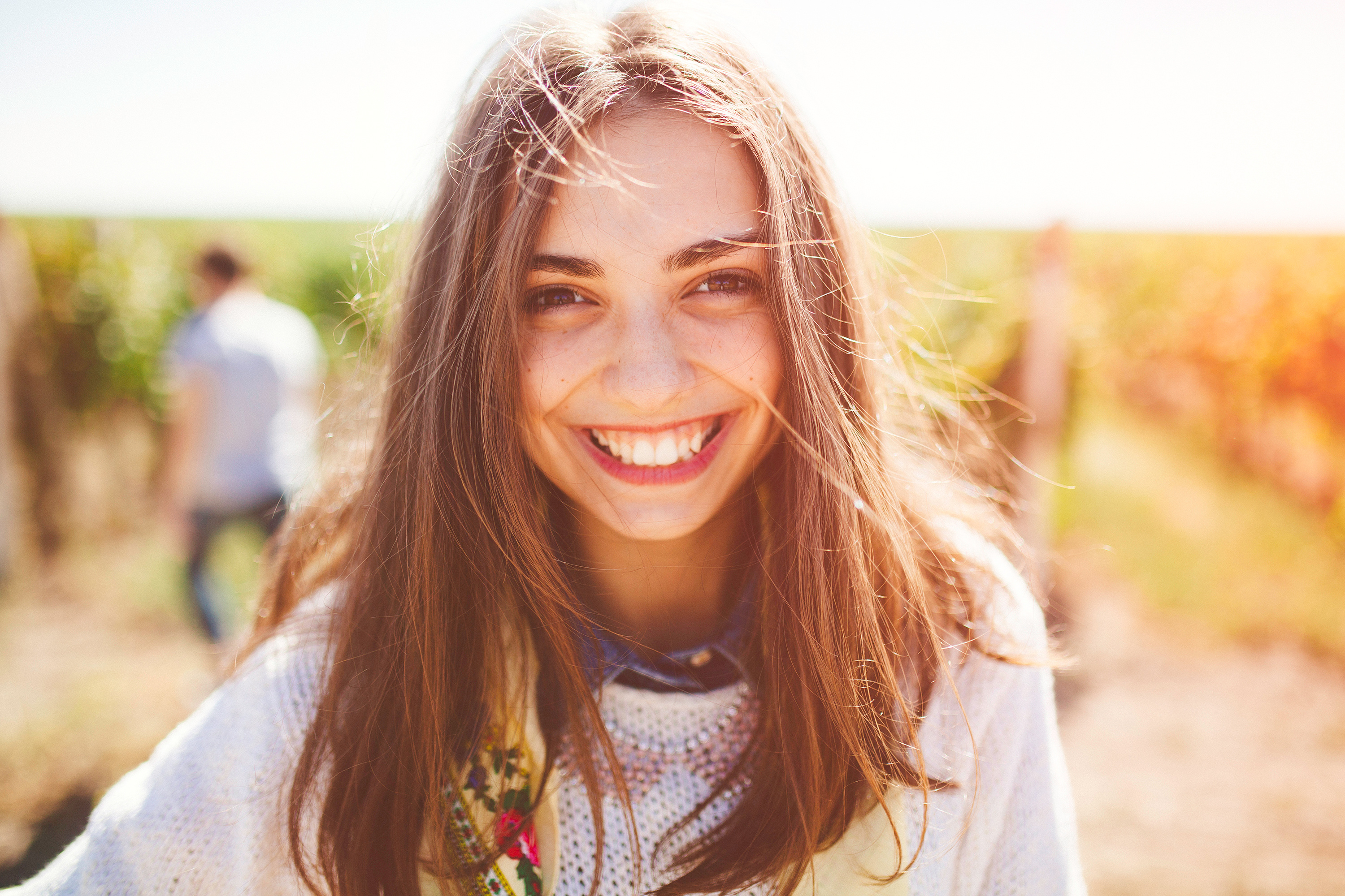 Smiling teenage girl outdoors on sunny day. Closeup of cute brunette young woman wearing casual clothes.