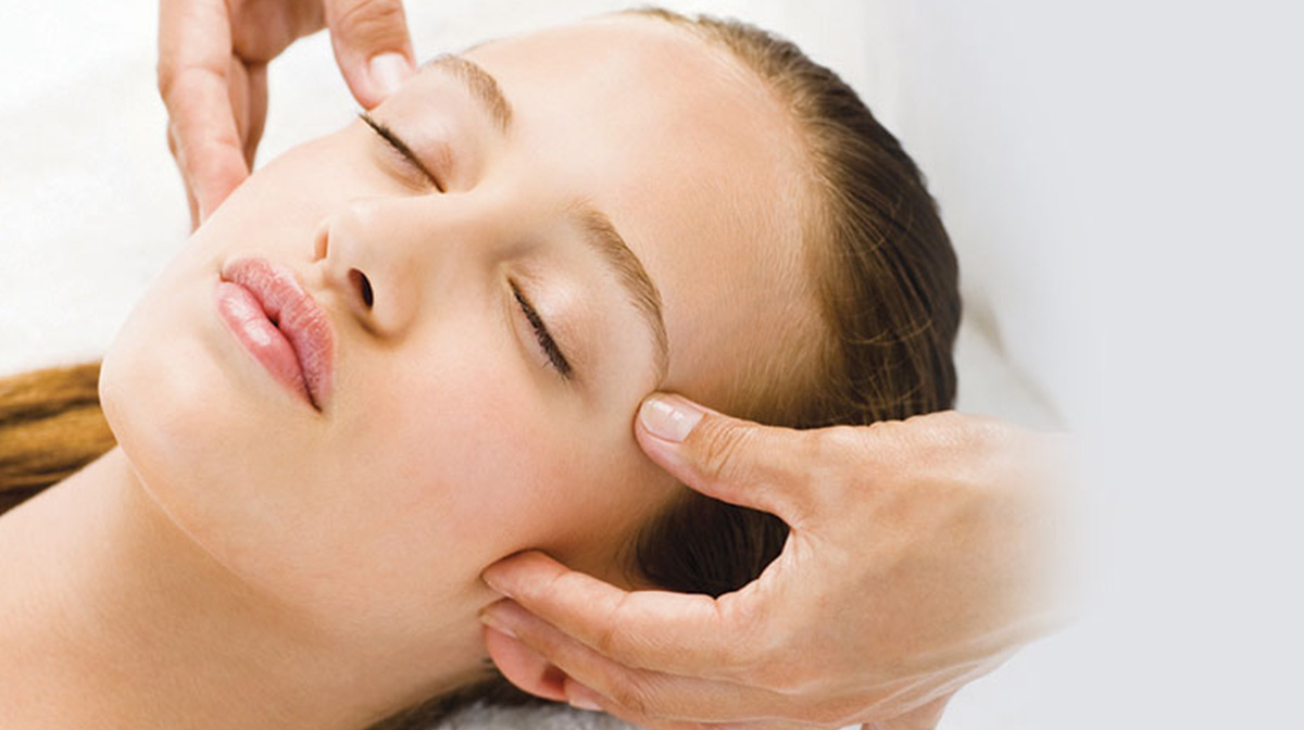 A woman closing her eyes enjoying a facial massage spa treatment