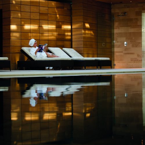 Lady relaxing on a sunbed in a spa in a dressing gown.