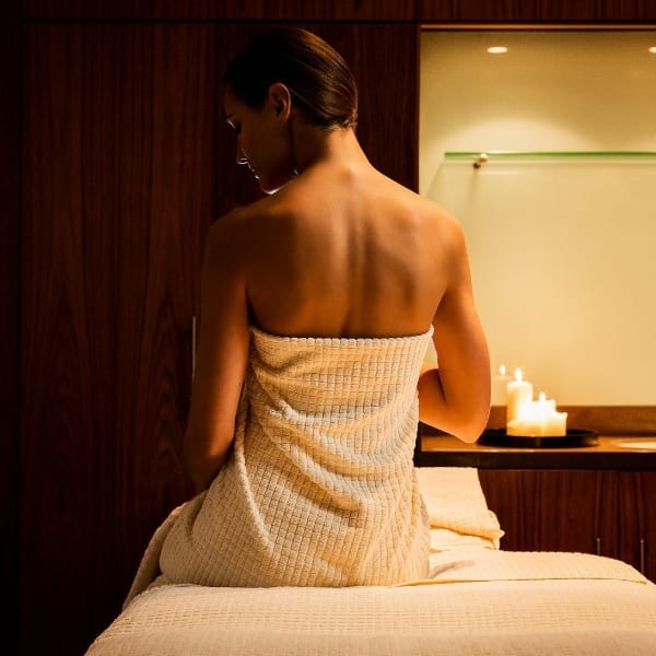 A woman sat on the therapist bed in a towel before a spa treatment