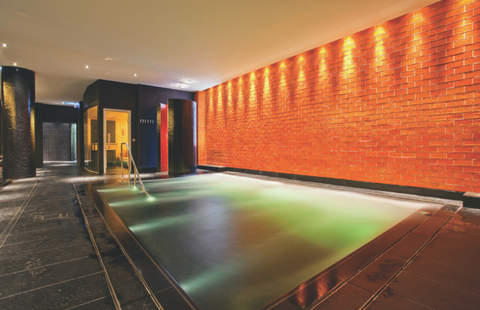 Indoor pool beside a brick wall in ESPA Riga 