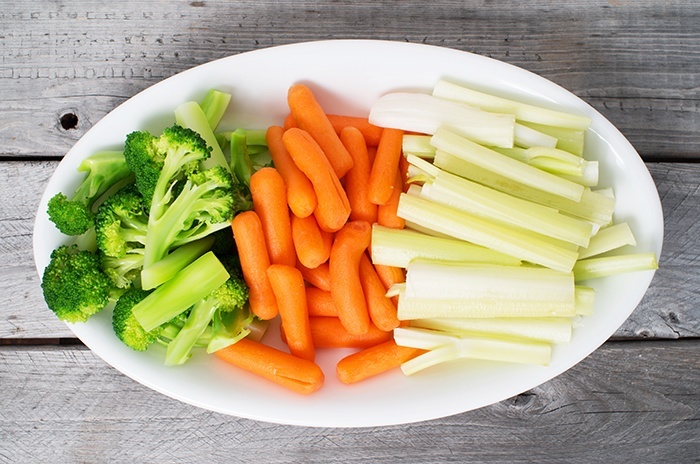 Vegetable tray with celery, broccoli, carrots on a wooden table
