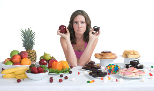 Woman sitting at table with many healthy and unhealthy food options placed before her