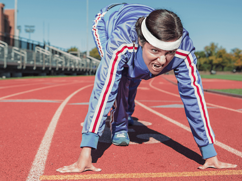 a woman wearing a track suit getting ready to run around the track