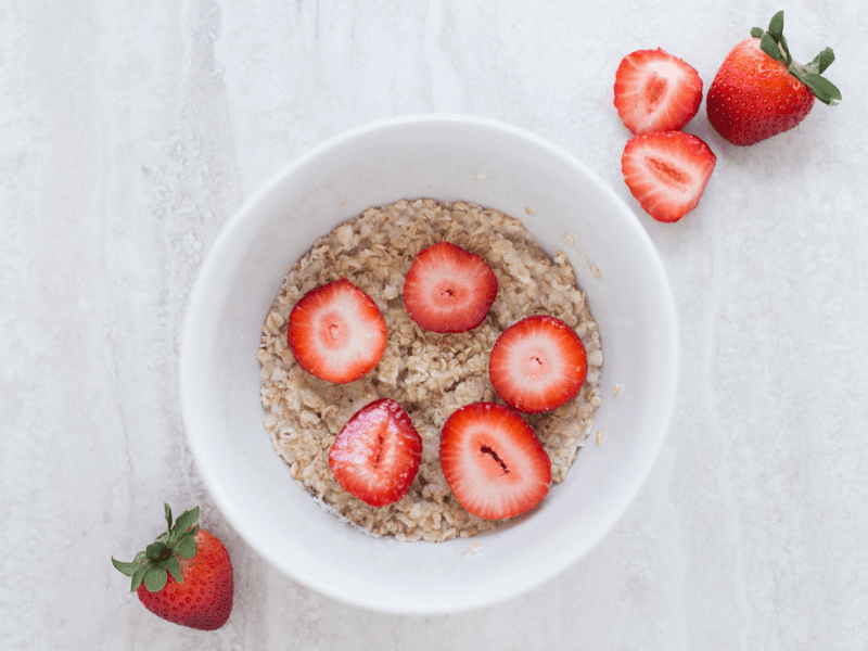 A bowl of oatmeal with some sliced strawberries