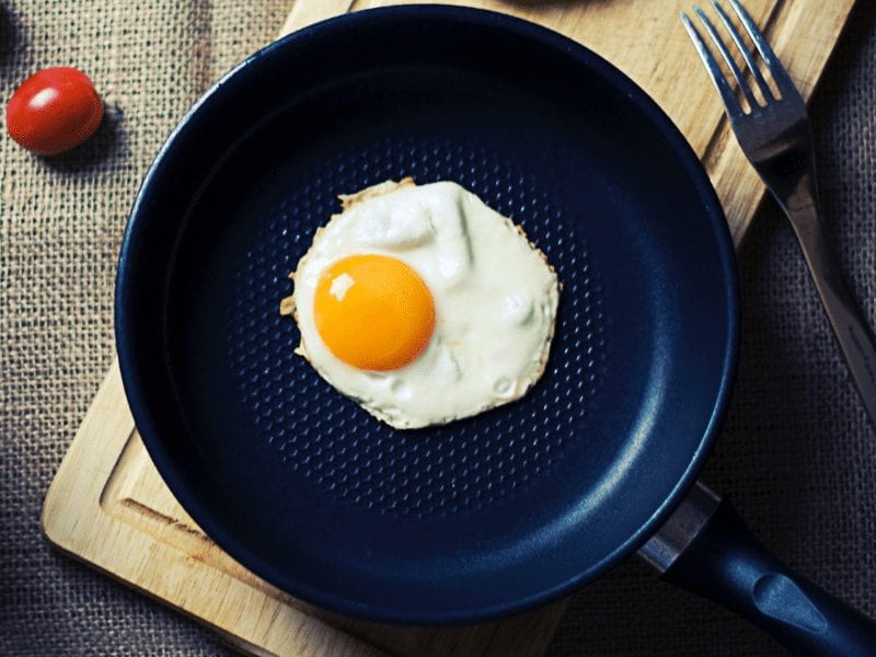 A fried egg in a black Teflon pan