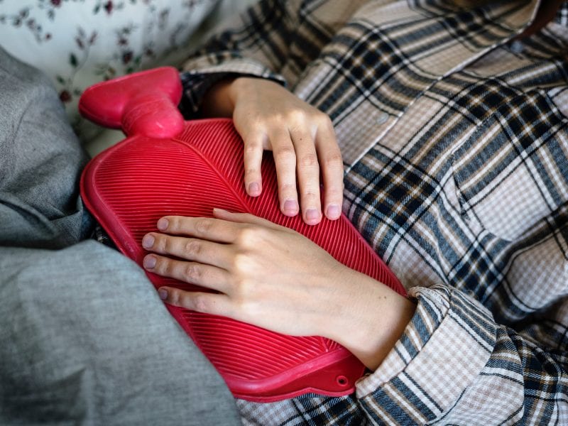 A woman holding a hot water bottle to her stomach after ingesting oils improperly