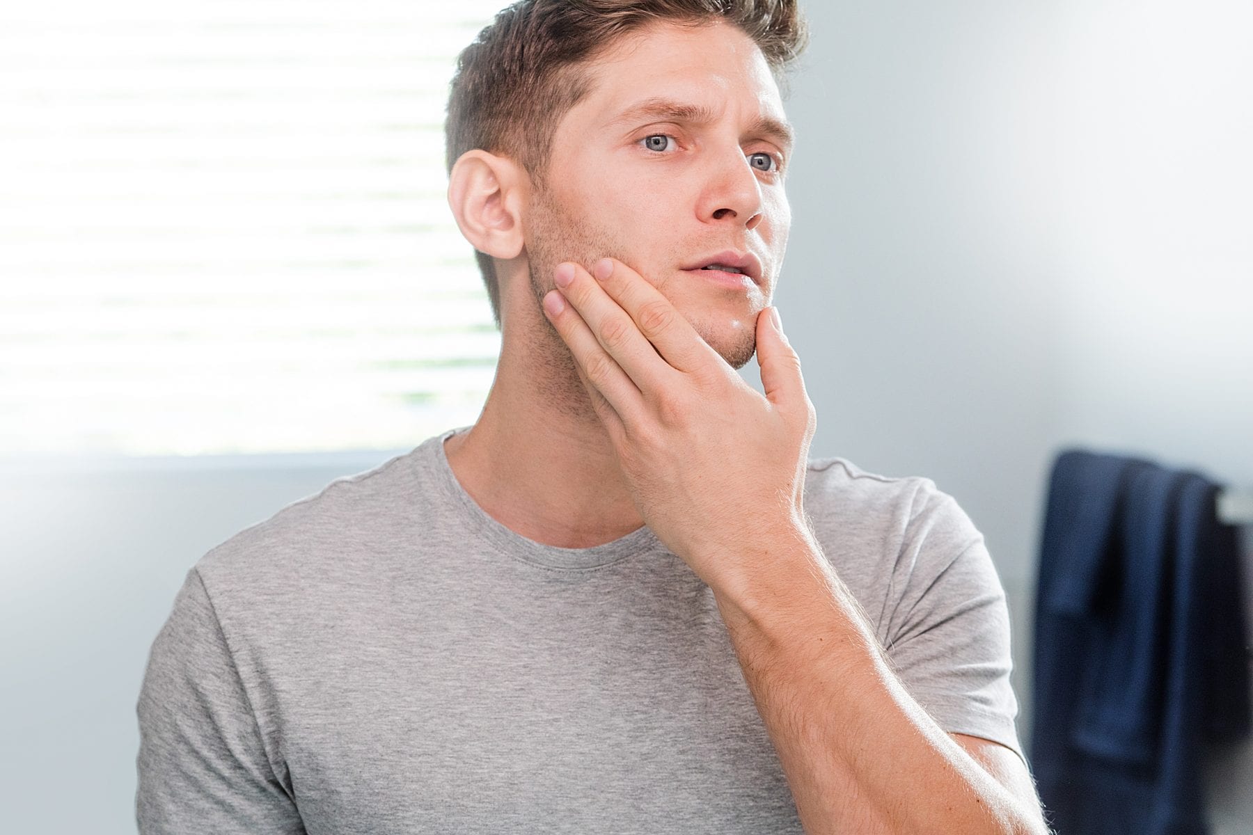 man rubbing hand across stubble