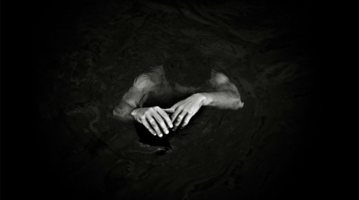 Benoit Courti Photography - a man almost submerged in dark water.