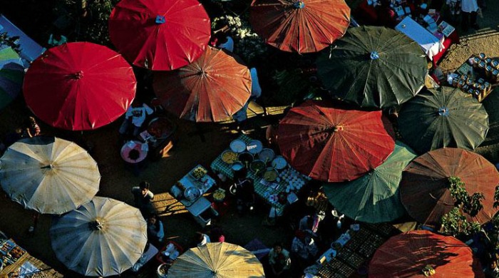 Yann Arthus Bertrand: a display of colourful parasols above a market stall.