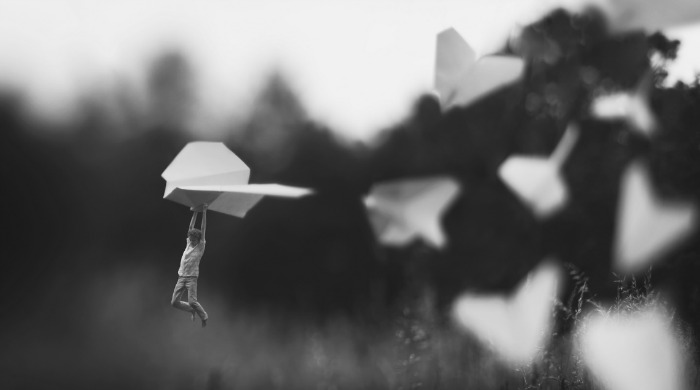 Miniature Landscapes by Fiddleoak: a small figure hang-gliding across a field on a small origami airplane.