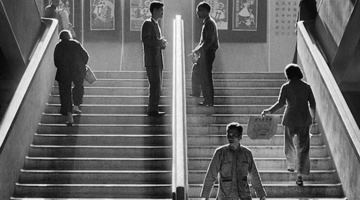 The Streets of 1950s Hong Kong Fan Ho: Civilians travelling up and down a stairway with two men meeting in the middle to talk.
