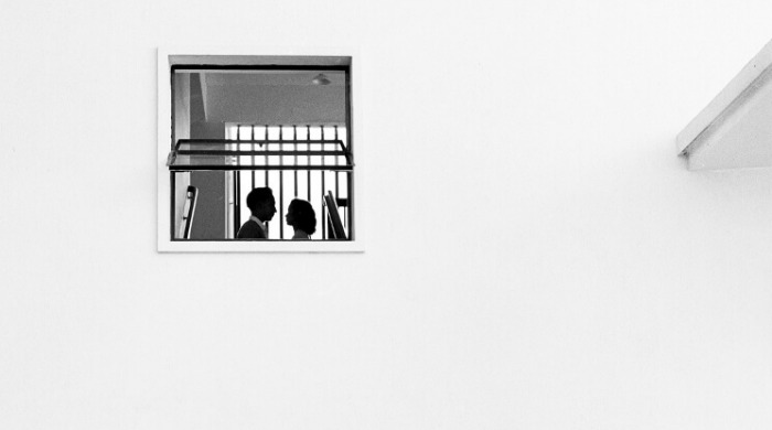 The Streets of 1950s Hong Kong Fan Ho: A small window on a white wall revealing a couple facing each other.