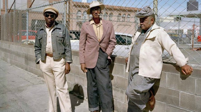 1970s San Francisco by Janet Delaney: Three men on a street against a concrete and wire mesh fence.