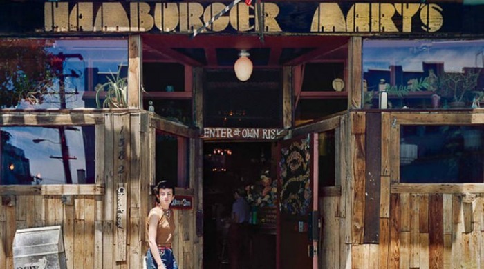 1970s San Francisco by Janet Delaney: A woman entering a restaurant named Hamburger Mary's, with a sign saying "enter at own risk".