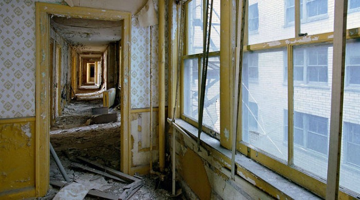 Ruins of Detroit Yves Marchand Romain Meffre: A view down a derelict corridor of doors with yellow borders.