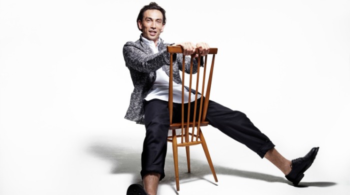 Oliver Spencer x Rankin: A man sitting backwards on a chair, leaning backwards with his legs spread apart.
