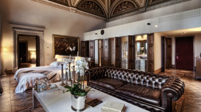 Il Salviatino, Florence: A room with a cream and dark brown colour scheme, including an ornate ceiling, white orchids for decoration and a dark brown leather sofa.