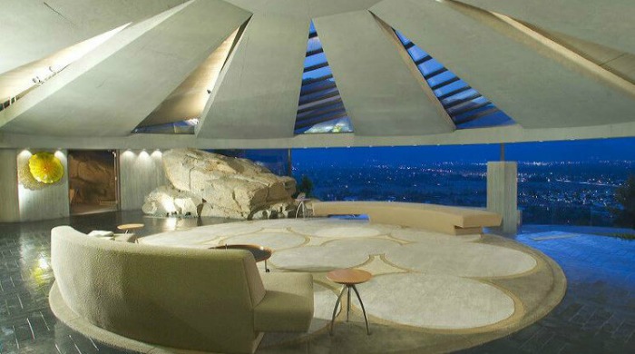 An open living in the Elrod House which looks onto a view of Palm Springs lit up at night.