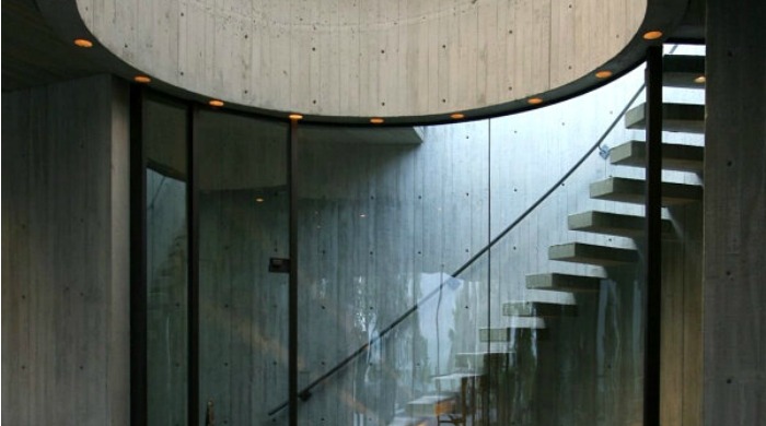 An interior shot in the Elrod House of a circular staircase behind a glass wall.