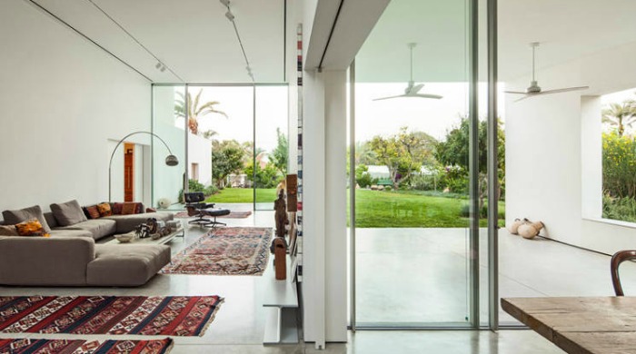 A spacious, open plan living area inside the T/A House with views through glass doors onto the garden.