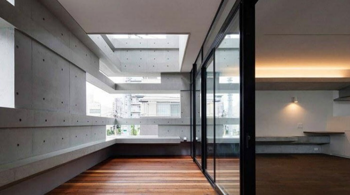 Inside the cranks house by Hugo Kohno with wooden flooring and open spaces in the exterior concrete walls.
