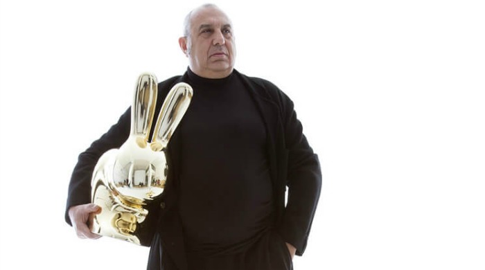 Stefano Giovannoni holding a large, golden, plastic rabbit made in collaboration with Qeeboo at Milan Design Week 2016.