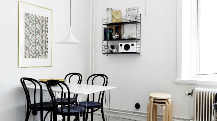 A minimal dining room with a gold picture frame and brass serving bowl on the table to show how metallics and copper can be used in the home.