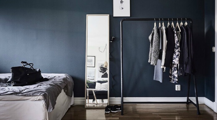 A bedroom incorporating the dark wall interior trend with dark blue walls, contrasted with soft brown floorboards.