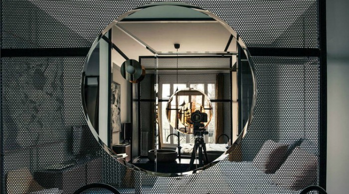 A view into the circular mirror being continually reflected in the bathroom of the 1930s apartment which is separated from the bedroom by a mesh partition.