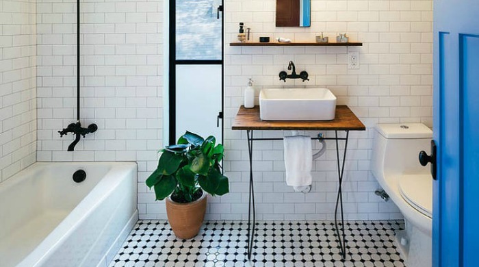 A monochrome bathroom with black and white tiled flooring, white tiled walls and black tab details.